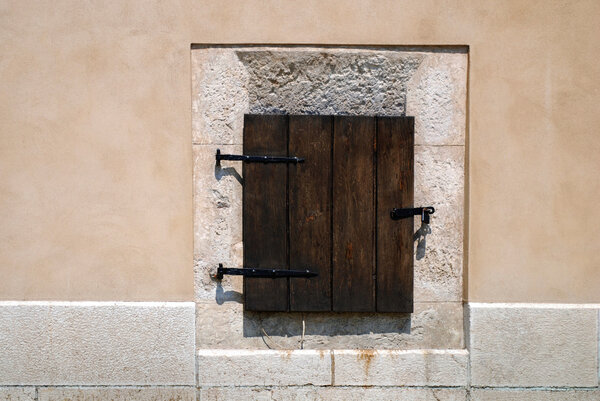 Closed wood window on aged stone wall with closed shutters