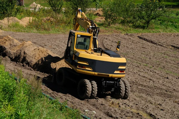Foto de una excavadora de trabajo en el campo — Foto de Stock