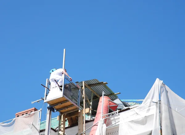 Кровельщик в шляпе на крыше дома летом — стоковое фото