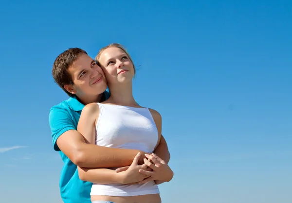 Молодая пара обнимается и смотрит в небо — стоковое фото