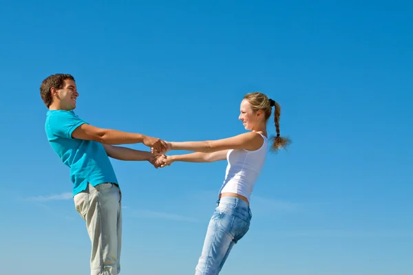Young couple holding hands against blue sky — Stock Photo, Image