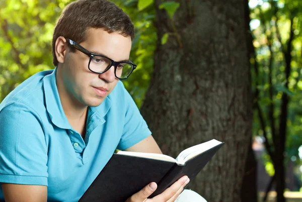 Junger Mann liest Buch im Park — Stockfoto