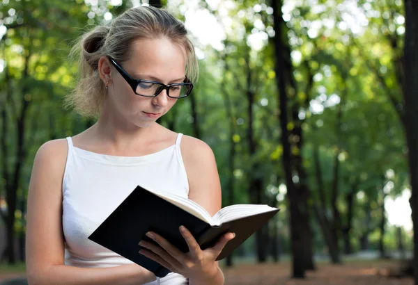 Young woman reading book in the park — Stock Photo, Image