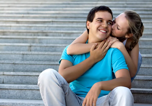 Young loving couple sitting on stairs and embracing — Stock Photo, Image