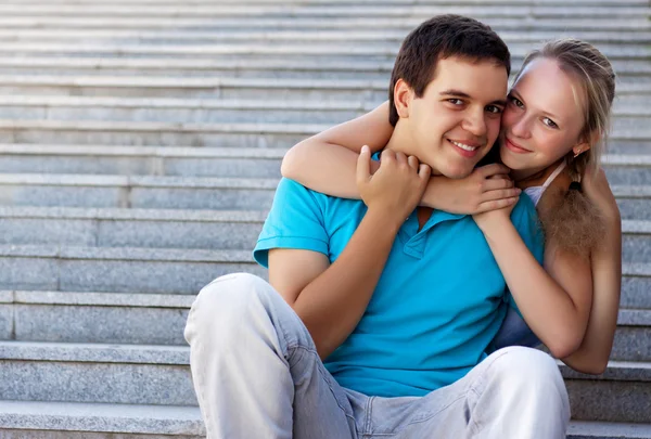 Young loving couple sitting on stairs and embrace — Stock Photo, Image