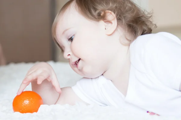 Little girl playing with tangerine — Stock Photo, Image