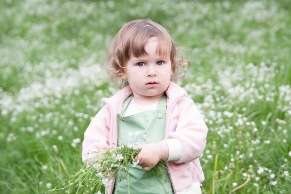 Kleines schönes Mädchen mit Blumenstrauß im grünen Frühling mea — Stockfoto