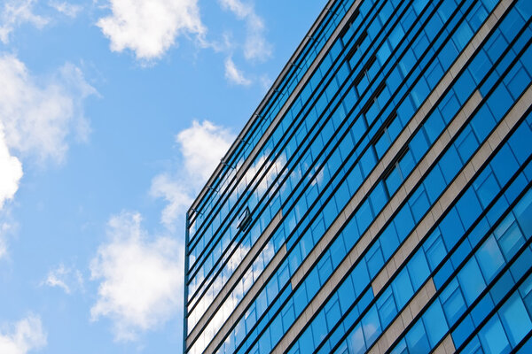 Blue sky and clouds reflecting in the glass of an office building
