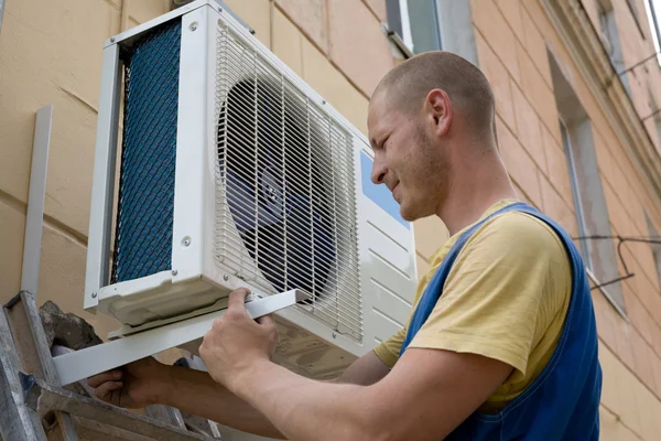 Installateur stelt een nieuwe air conditioner Stockfoto