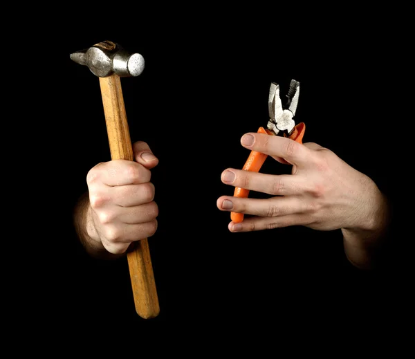 Manos sosteniendo martillo y alicates. Aislado sobre fondo negro — Foto de Stock