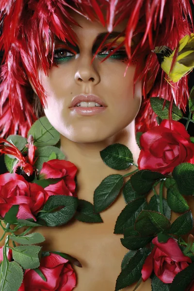 De jonge vrouw met een rode veren en kleuren Stockfoto
