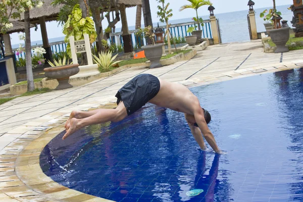 Человек пытается прыгнуть в воду в бассейне — стоковое фото