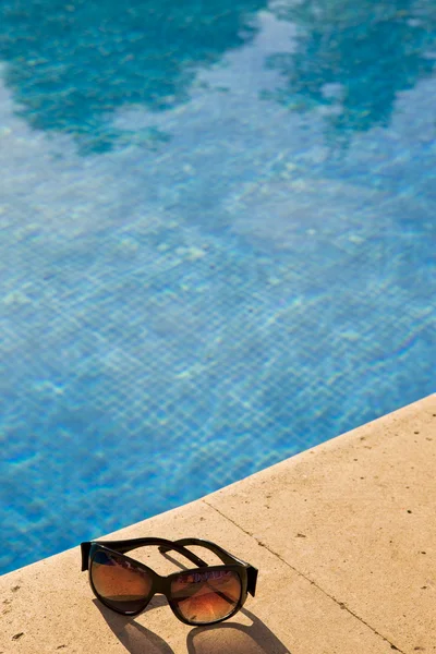 Gafas de sol se encuentra al borde de la piscina — Foto de Stock