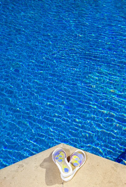 Тапочки лежат на краю бассейна — стоковое фото