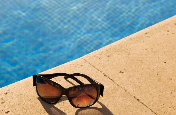 Gafas de sol se encuentra al borde de la piscina —  Fotos de Stock