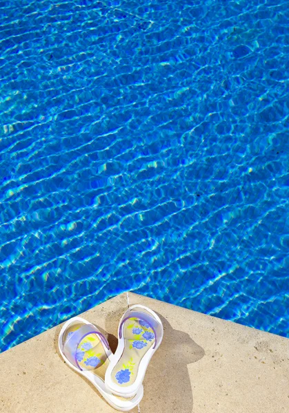 Zapatillas se encuentra al borde de la piscina — Foto de Stock