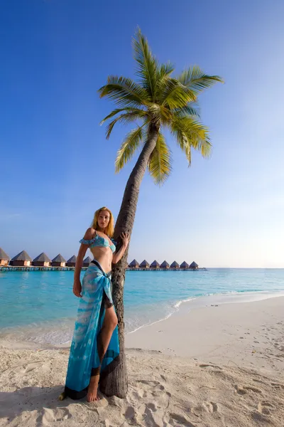Молодая красивая девушка стоит рядом с пальмой на фоне океана, Мальди — стоковое фото