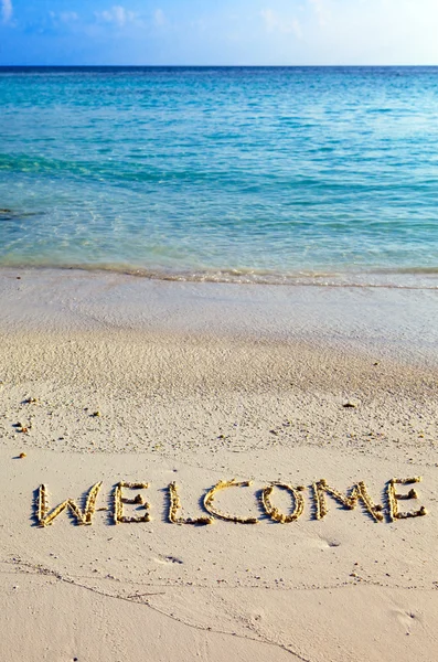 Слово " Ласкаво просимо " написано на піску на узбережжі океану — стокове фото