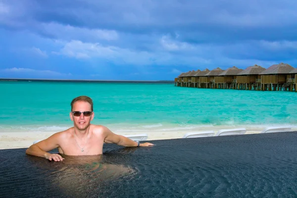L'uomo in piscina e l'oceano sullo sfondo. Maldive . — Foto Stock
