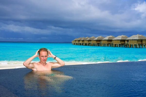 Giovane uomo sportivo in piscina e nell'oceano sullo sfondo . — Foto Stock