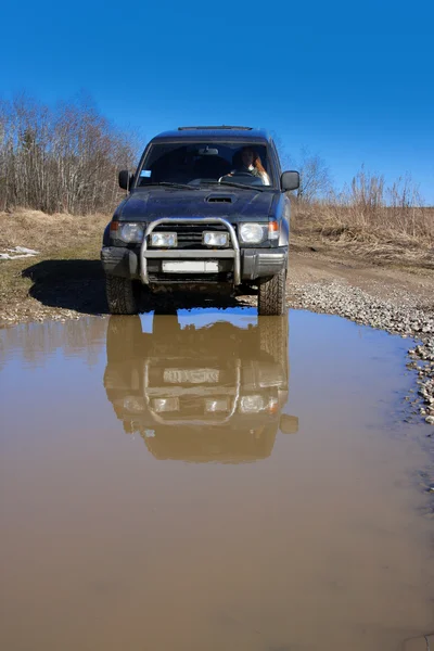 Young woman behind rudder of offroad car on dirt road before water obstacle — Stock Photo, Image