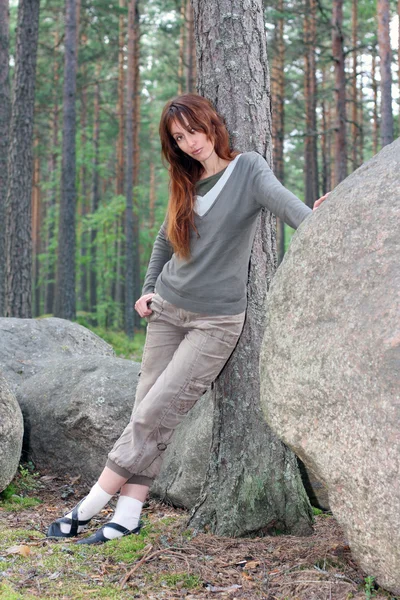 Young woman in pine forest near by big stones — Stock Photo, Image