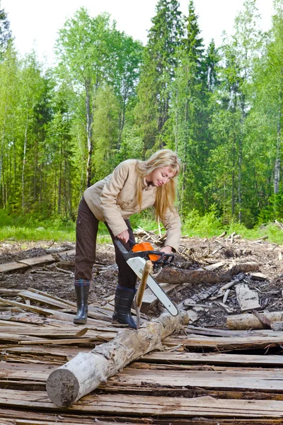 Frau in Holz sägt Baum mit Kettensäge — Stockfoto