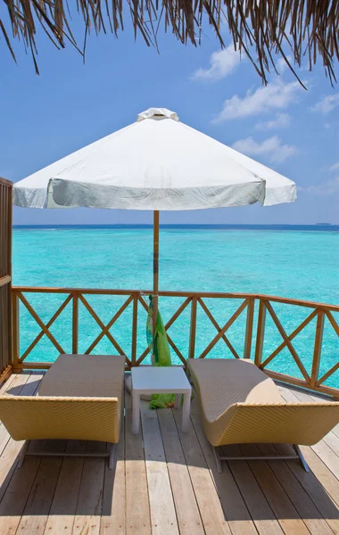 Slunečník a lehátko salonků, na terase vodní vily, Maledivy. — Stock fotografie
