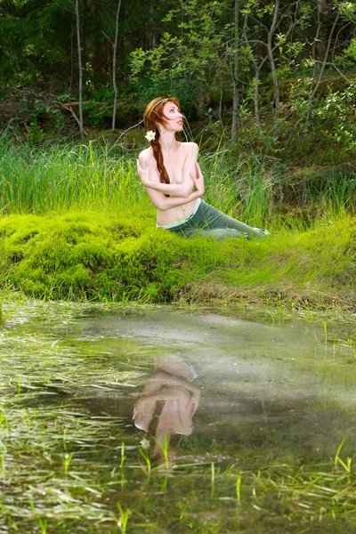 The girl sits on the bank of wood lake — Stock Photo, Image
