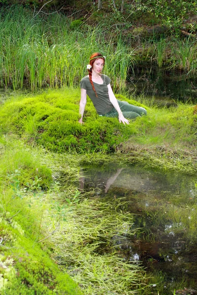 La chica se sienta en la orilla del lago de madera — Foto de Stock