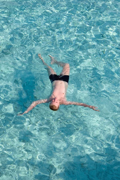 Le garçon se repose sur l'eau transparente de l'océan — Photo