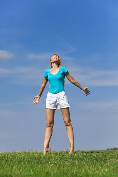 예쁜 젊은 여 자가 밝게 어두운 푸른 하늘에 대하여 녹색 잔디에 점프 — 스톡 사진