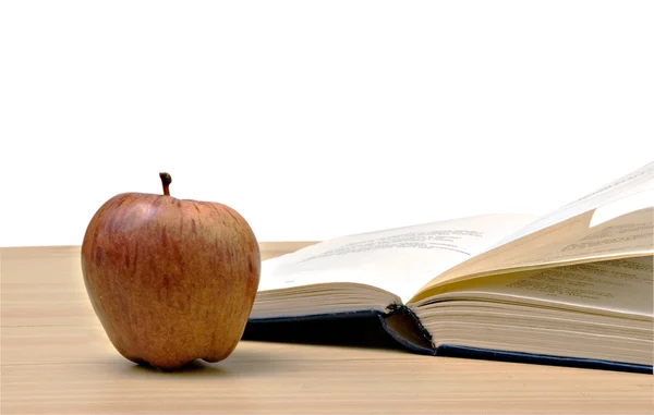 Rött äpple och öppen bok på skrivbord — Stockfoto