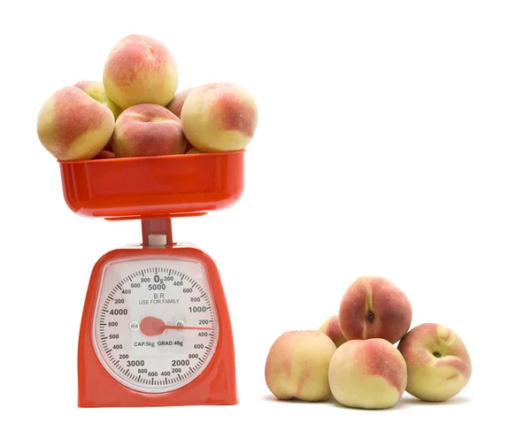 红色厨房秤称重的桃子 — 图库照片