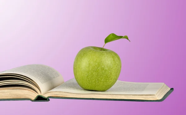 Açık kitap üzerine yeşil elma — Stok fotoğraf