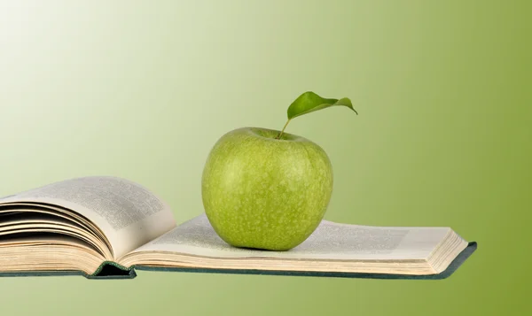 Green apple on open book — Stock Photo, Image