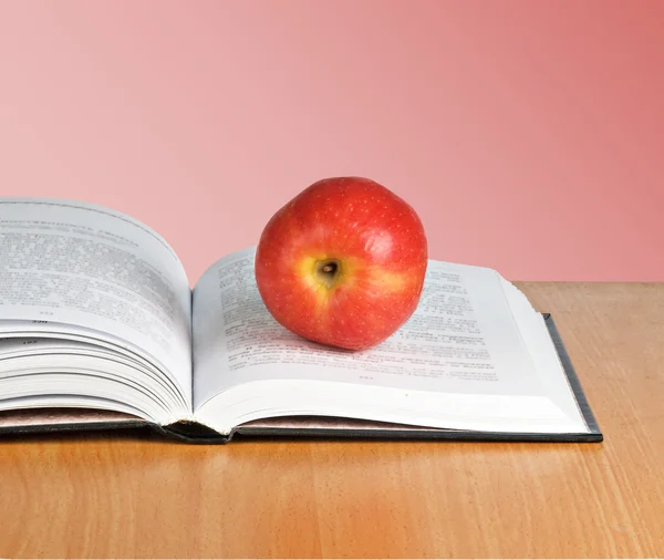 Açık kitap üzerine kırmızı elma — Stok fotoğraf