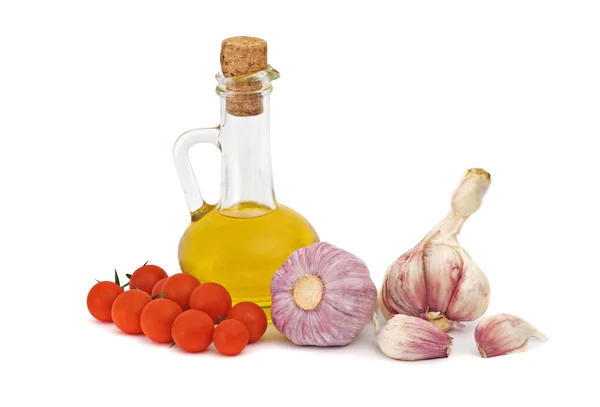 Бутылка оливкового масла, чеснока и помидоров черри на столе — стоковое фото