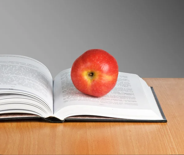 Manzana en el libro sobre fondo gris — Foto de Stock