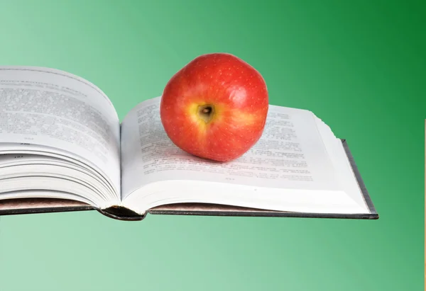 Roter Apfel auf aufgeschlagenem Buch — Stockfoto