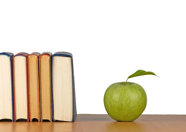 Яблоко и книги на столе — стоковое фото