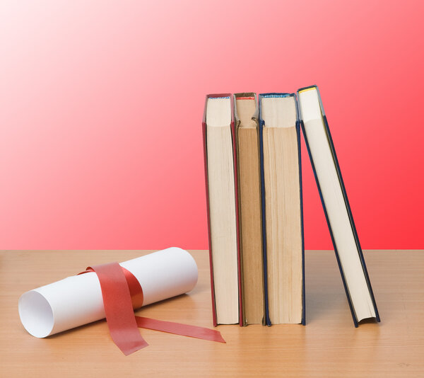 Scroll with red ribbon and books