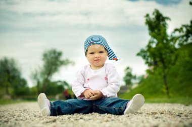 Beautiful child plays on a stones road clipart