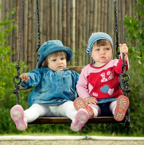 Двоє дітей на гойдалках — стокове фото