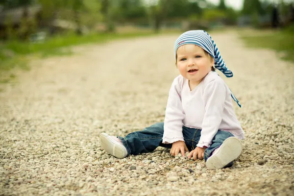 Beautiful child plays on a stones road — Stock Photo, Image