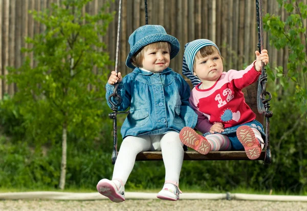Двое детей на качелях в парке — стоковое фото