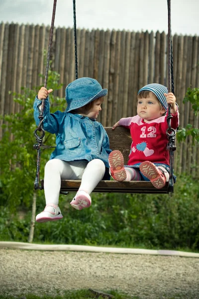 Duas crianças nos baloiços no parque — Fotografia de Stock