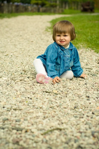 Bela criança joga em uma estrada de pedras — Fotografia de Stock