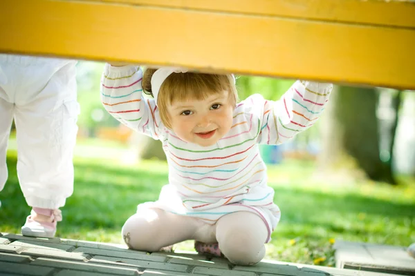 Девушка играет в прятки под скамейкой — стоковое фото