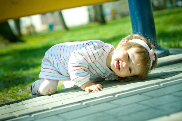 Девушка играет в прятки под скамейкой — стоковое фото